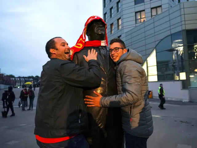 Arsenal fans pose for a picture with the Herbert Chapman statue outside the Emirates stadium
