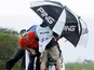 Mark Wilson and his caddy hide behind their umbrella during the windy weather in Hawaii on January 7, 2013